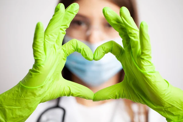 Vrouwelijke arts in witte vacht toont hand een hart teken — Stockfoto