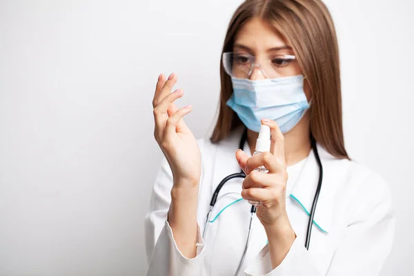 하얀 코트를 입고 있는 여자 의사는 살균제로 손을 소독 한다 — 스톡 사진