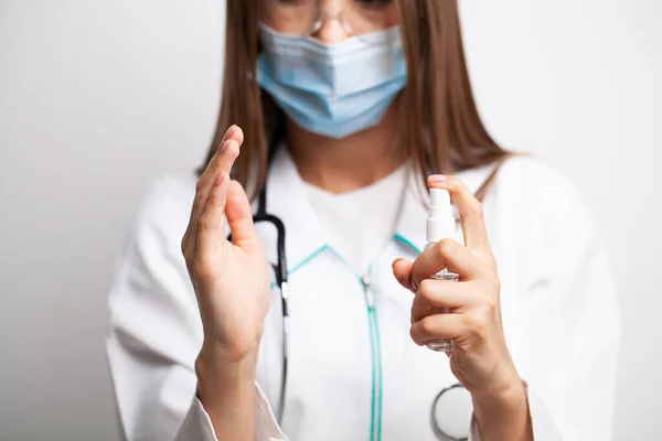 La doctora con una bata blanca desinfecta sus manos con antiséptico — Foto de Stock