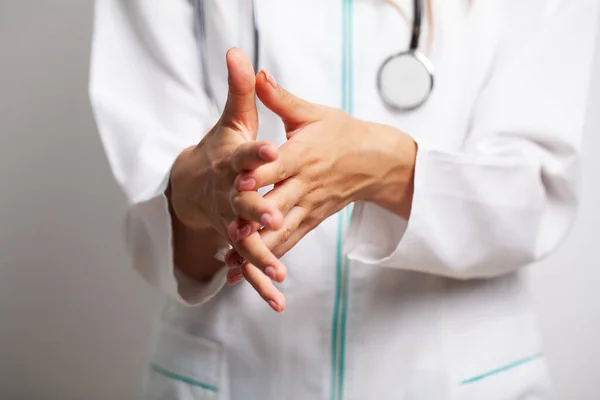 Médica de casaco branco desinfecta as mãos com anti-séptico — Fotografia de Stock