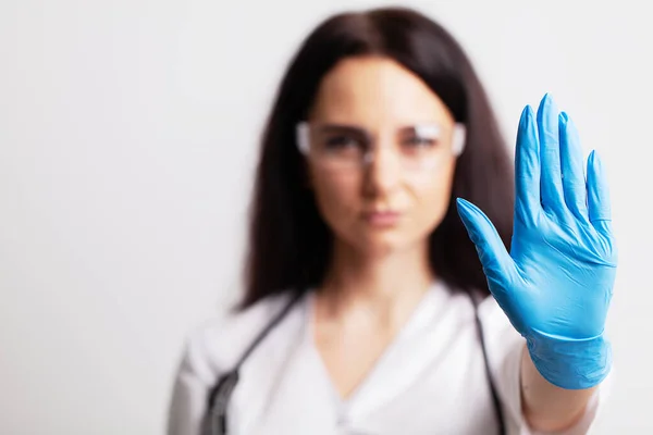 Médica feminina de casaco branco mostra parada de mão — Fotografia de Stock