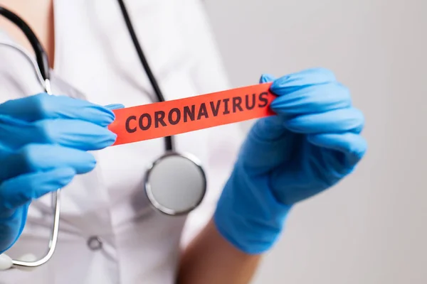 Beyaz önlüklü kadın doktor Coronavirus yazısını tutuyor. — Stok fotoğraf