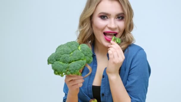 Donna in cucina che mangia broccoli freschi — Video Stock