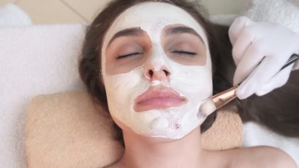 Ett spa. Attraktiv rolig kvinna med en lermask i ansiktet. — Stockvideo