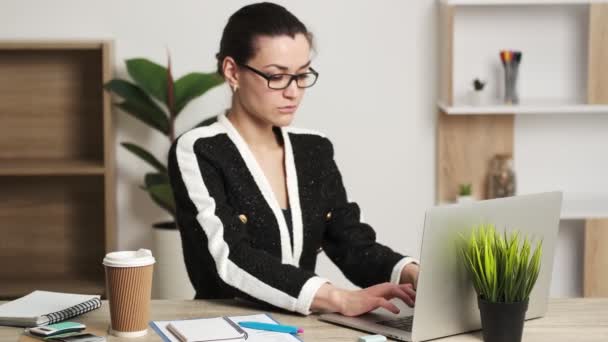 Aantrekkelijke zakenvrouw werkt op laptop in haar werkstation. — Stockvideo