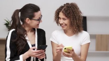 İki genç iş kadını cep telefonunda mesaj arıyor.