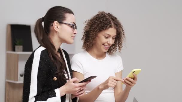 Két fiatal üzletasszony SMS-t keres a mobilján. — Stock videók
