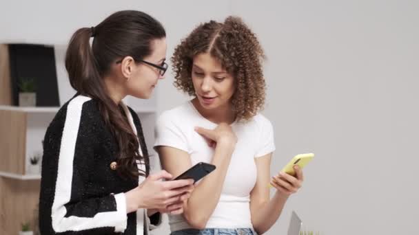 Две молодые деловые женщины проверяют мобильный телефон на наличие смс — стоковое видео