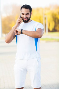 Adam dışarıda spor yapıyor ve telefonda konuşuyor.