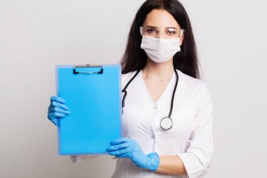 Eldivenli, maskeli ve gözlüklü doktor mesaj için boş bir form tutuyor.