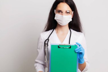 Eldivenli, maskeli ve gözlüklü doktor mesaj için boş bir form tutuyor.