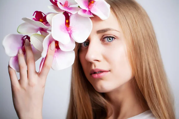 Naturkosmetik, schönes Frauengesicht mit Orchidee. — Stockfoto