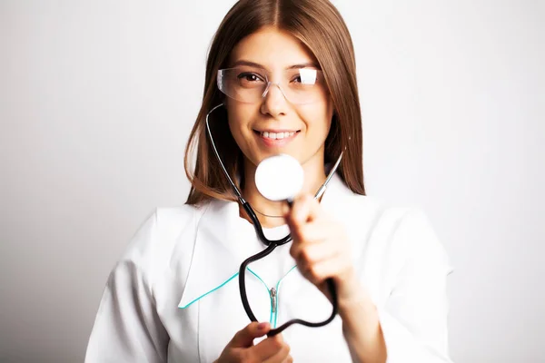 Doctor with protective goggles and stethoscope on her workspace — Stock Photo, Image
