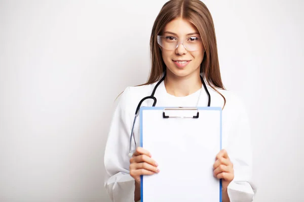 Doctor in a gloves, mask and glasses holds a blank form with space for text — Stock Photo, Image