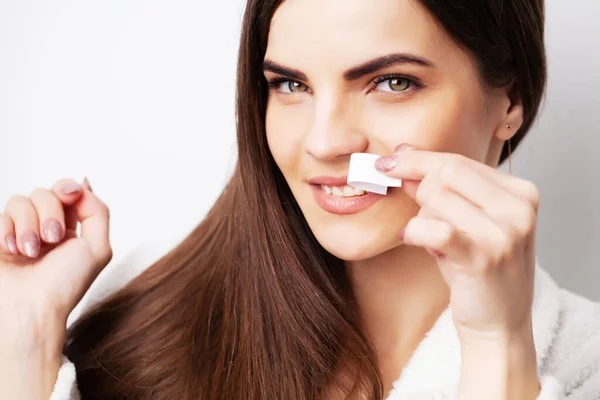 Young woman doing waxing in the area above the eyebrows