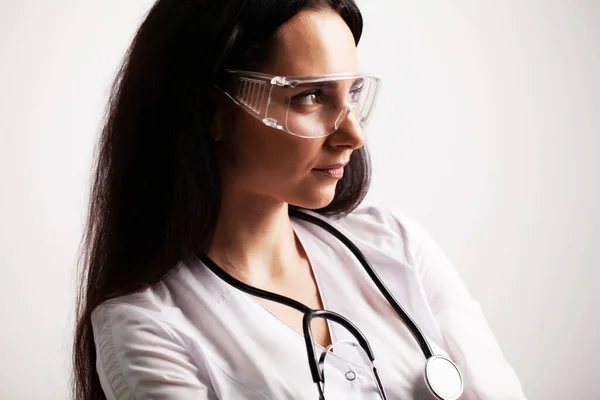 Médico com óculos de proteção e estetoscópio em seu espaço de trabalho — Fotografia de Stock