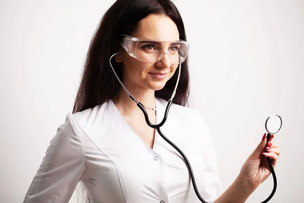 Doctor with protective goggles and stethoscope on her workspace — Stock Photo, Image