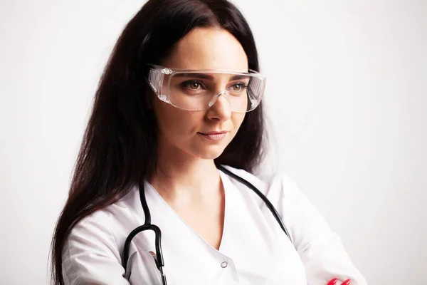 Doctor with protective goggles and stethoscope on her workspace — Stock Photo, Image