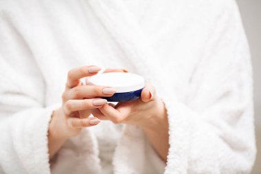 Kadın cilt bakımı için nemlendirici tutuyor.