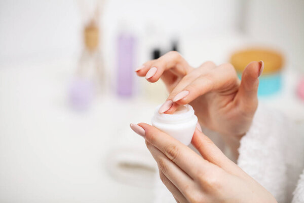 Woman close up holding moisturizer for skin care