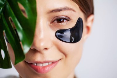 Göz bandı, doğal makyajlı güzel bir kadın ve yüz derisinde siyah jel göz bantları.