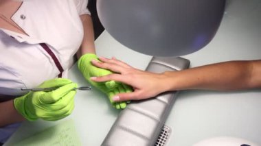 Manikürcü bir güzellik stüdyosunda Fransız manikürü yapıyor.