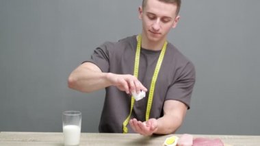 Sağlıklı beslenme konsepti. Güçlü adam tabletlere takviye alıyor ve yüksek protein içeren sağlıklı yiyecekler yiyor.