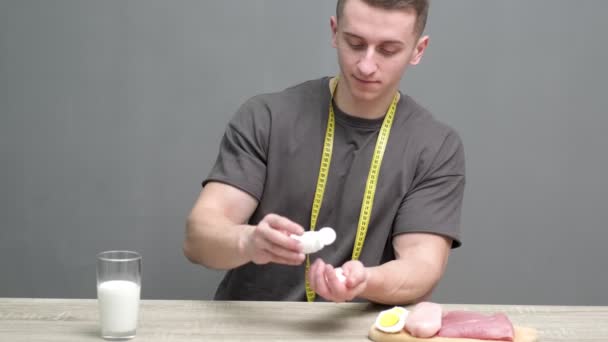 Concepto de alimentación saludable. Hombre fuerte toma suplementos en tabletas y come alimentos saludables ricos en proteínas — Vídeo de stock