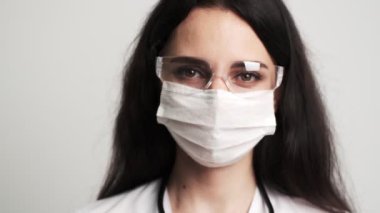 Beyaz önlüklü kadın doktor cerrahi maske kullanıyor..