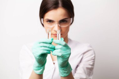 Tıp konsepti, klinikteki doktor kadın deney aşısıyla test tüpleri tutuyor.