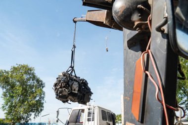 Bir forklift ve işçiler eski bir arabanın motorunu geri dönüşüm için kaldırıyorlar..
