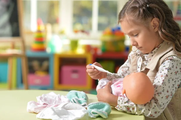 Flicka som leker med baby doll — Stockfoto