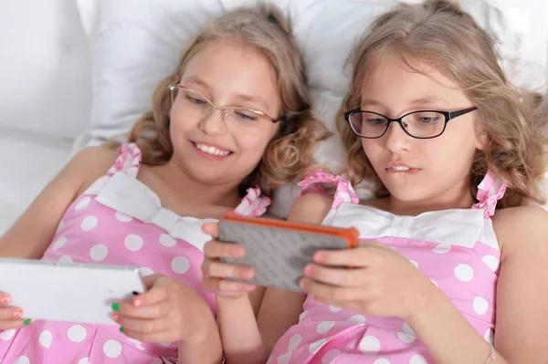 Twee zussen tweeling met behulp van slimme telefoons — Stockfoto