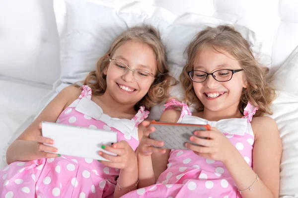 To søstre tvillinger ved hjælp af smartphones - Stock-foto
