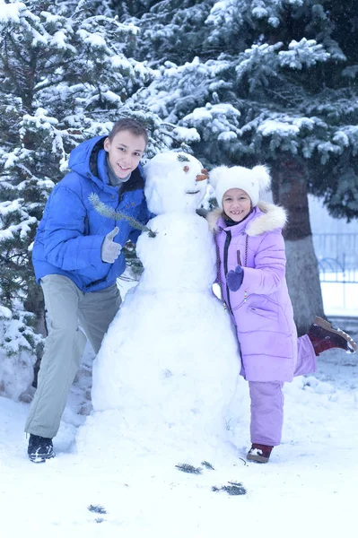 Broer en zus een sneeuwpop maken — Stockfoto