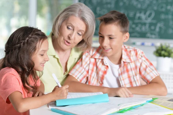 Oma mit Enkeln bei den Hausaufgaben — Stockfoto