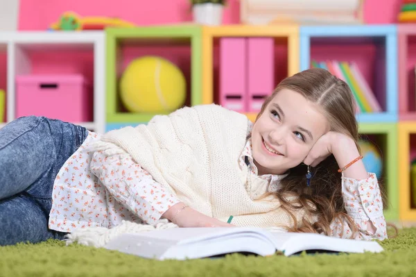 Little girl lying on green carpet — Stock Photo, Image