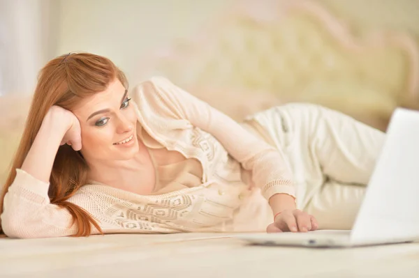 Mladá žena leží na podlaze s notebookem — Stock fotografie