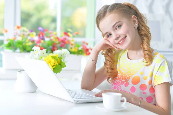 Menina sentada à mesa com laptop — Fotografia de Stock