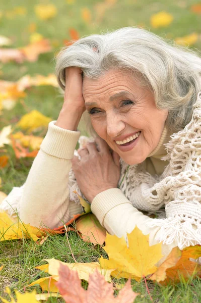 Senior woman lying on green grass — Stock Photo, Image