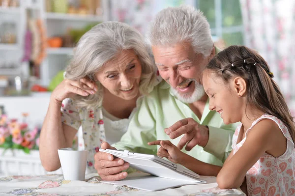 Девушка с бабушкой и дедушкой с помощью планшета — стоковое фото