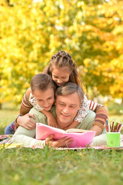 Família descansando no parque com livro — Fotografia de Stock