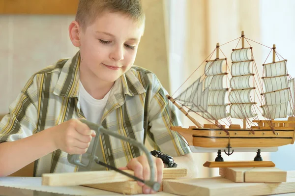 Niño con modelo de nave y sierra de mano — Foto de Stock