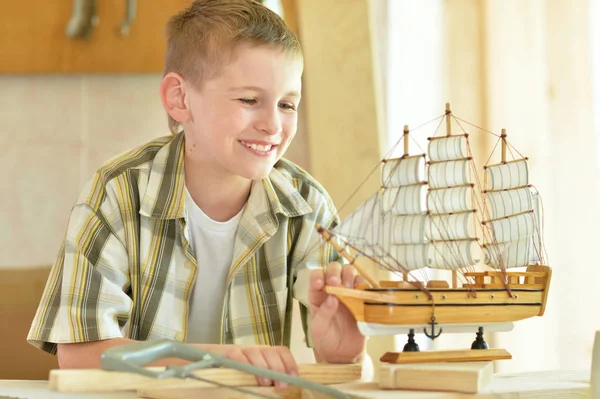 Boy with model of ship and handsaw — Stock Photo, Image