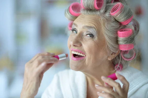 Senior woman applying pink lipstick — Stock Photo, Image