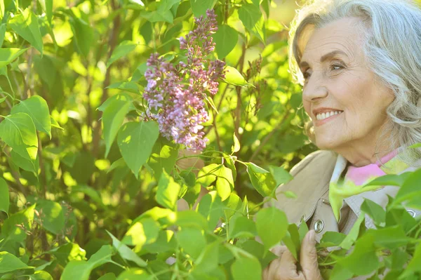 Senior vrouw in de buurt van bloeiende boom — Stockfoto