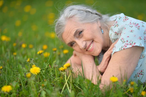 Senior woman lying on meadow — Stock Photo, Image