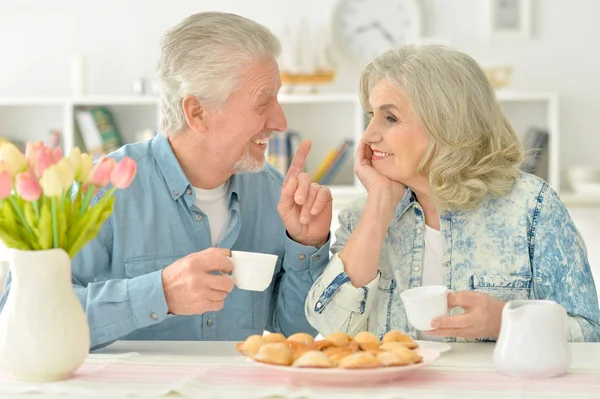 Casal sênior beber chá com biscoitos — Fotografia de Stock