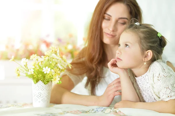 Madre con hija pequeña sentada a la mesa —  Fotos de Stock