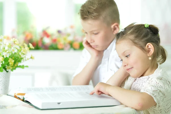 Children sitting at table and reading — Stock Photo, Image